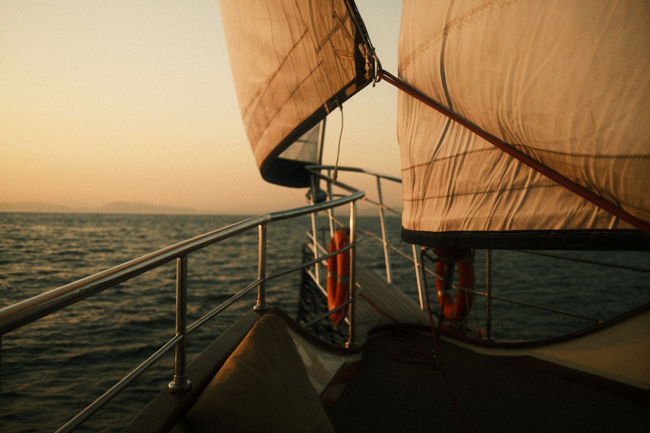 Home A serene sunset view from a sailboat on the open sea, capturing the beauty of sailing.