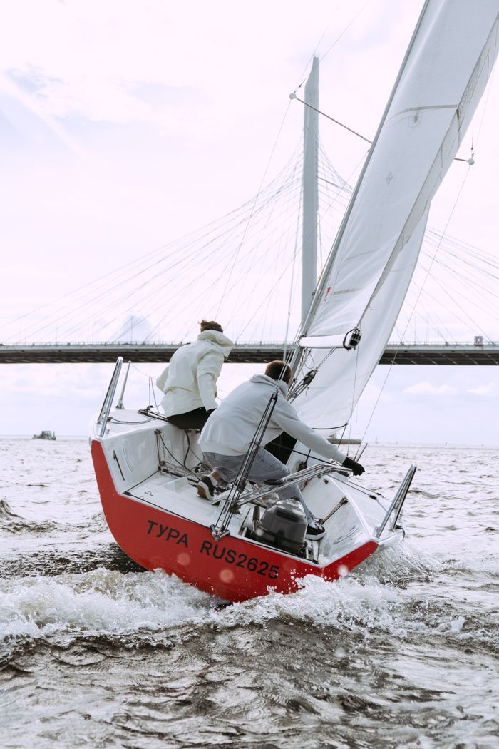 Home Dynamic sailboat racing under a suspension bridge on a windy day.