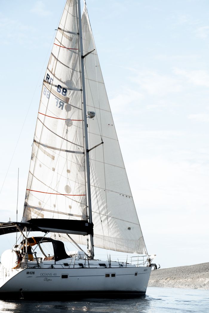 Home Sailboat gliding on tranquil water beneath a clear sky, capturing a serene nautical scene.